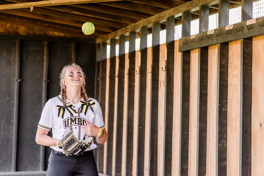 Sample image - student athlete throws softball in the air and smiles