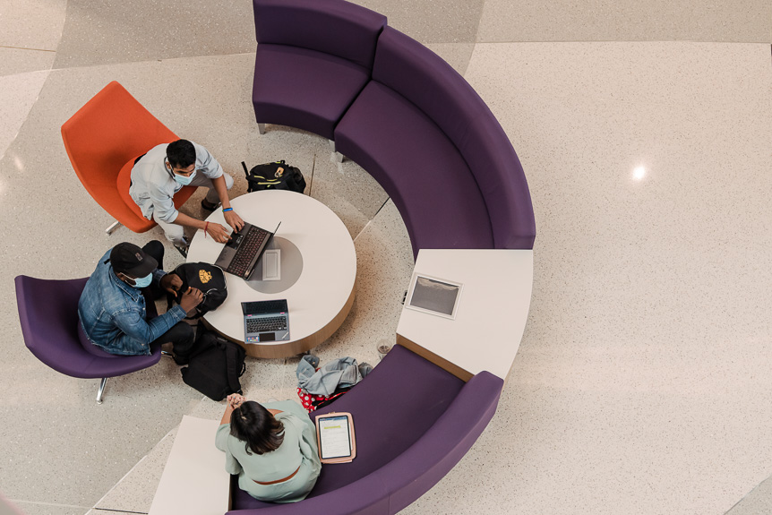 Sample image - photo from above of students studying on laptops sitting around a circular table in ILSB