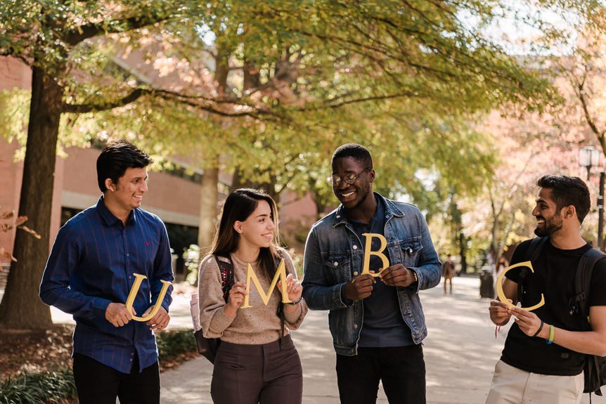Sample image - students smile holding UMBC letters on academic row